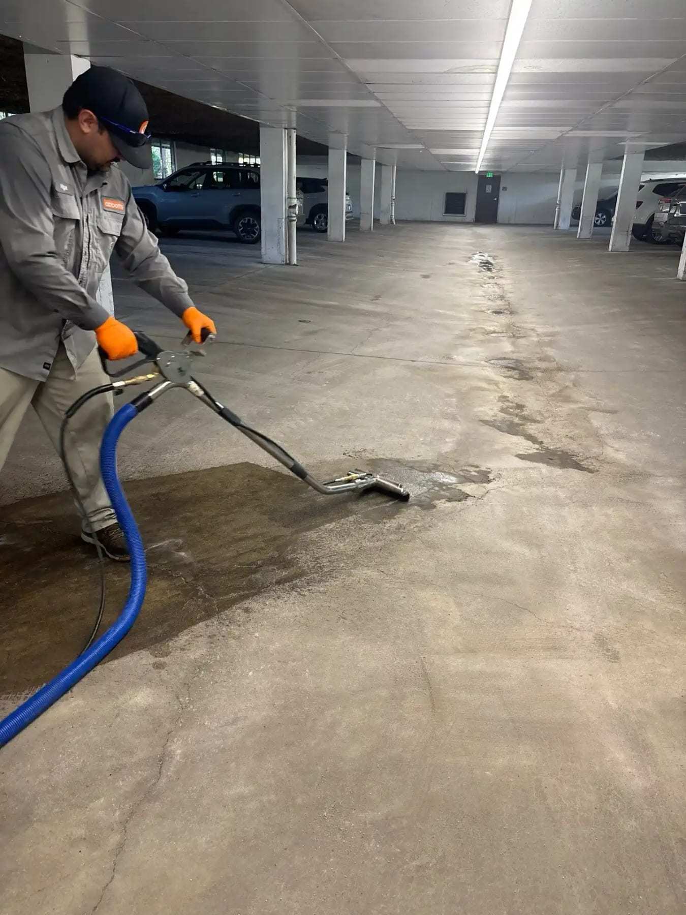 Technician extracting water from the floor of a parking garage